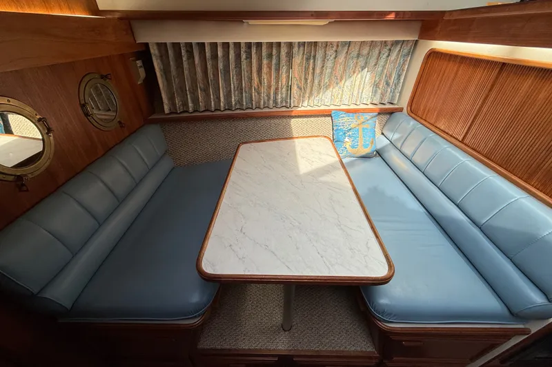Slide: The Image of 1989 Carver 3807 Aft Cabin Motor Yacht interior with blue seating and marble table. - 50