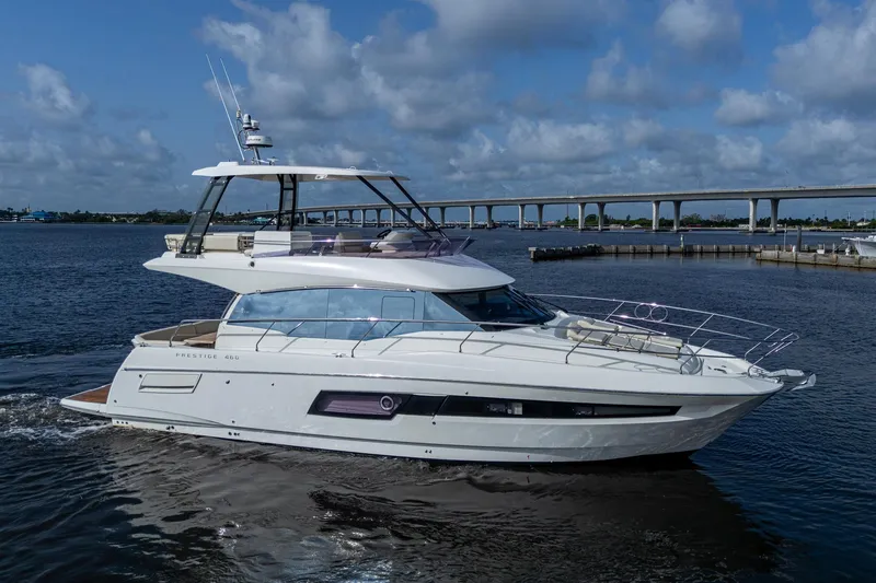 Slide: The Image of 2019 Prestige 460 yacht cruising on a calm river under a cloudy sky. - 1