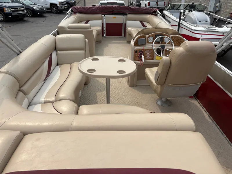 Slide: The Image of The image shows the interior of a 2012 Crest Classic 230L pontoon boat with beige seating. - 17