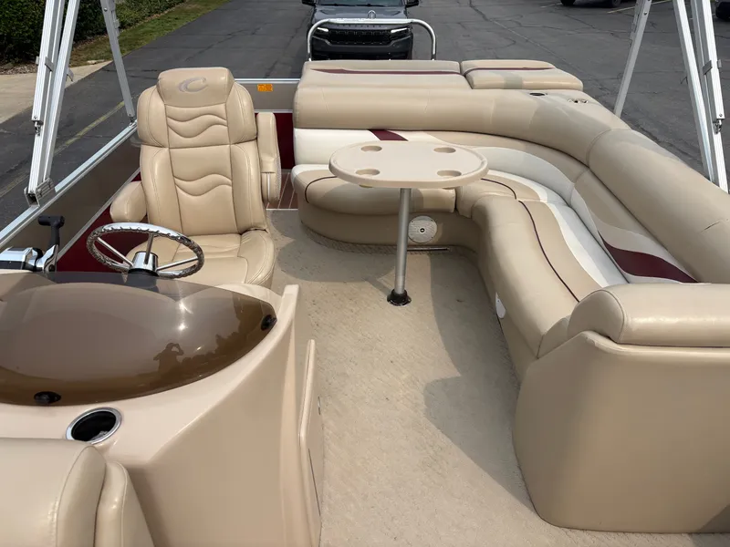 Slide: The Image of The image shows the interior of a 2012 Crest Classic 230L pontoon boat with beige leather seating and a round table. - 11