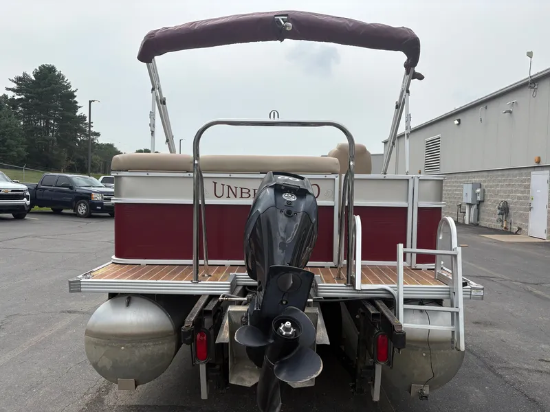 Slide: The Image of A 2012 Crest Classic 230L pontoon boat with an outboard motor, parked on a trailer. - 6