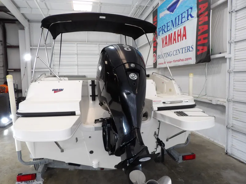 Slide: The Image of A 2013 Bayliner 190 Deck Boat with an outboard motor in a storage facility. - 8