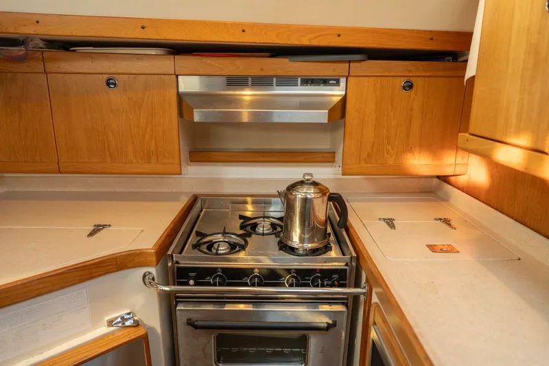 Slide: The Image of Galley kitchen in 2000 Catalina 400 MkII yacht with stove and wooden cabinetry. - 23
