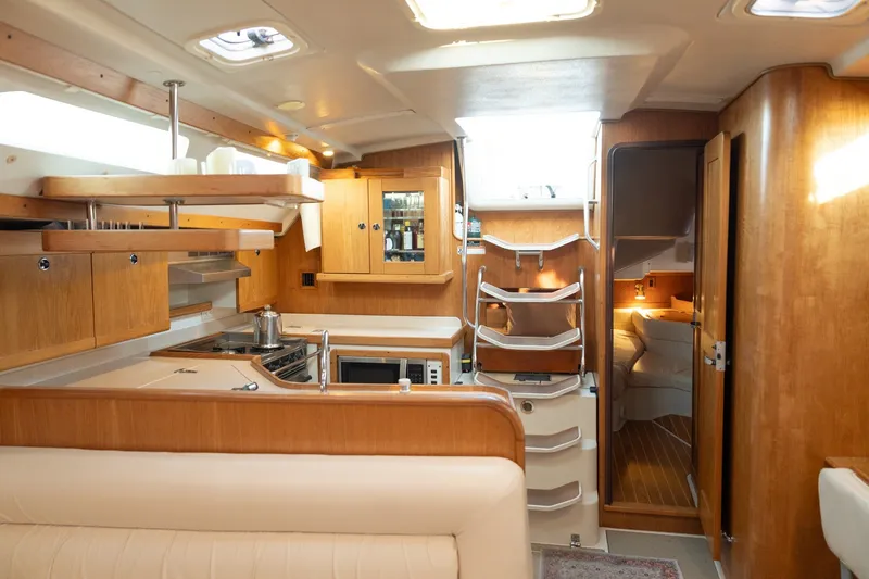 Slide: The Image of Interior of a 2000 Catalina 400 MkII yacht, featuring a cozy kitchen and dining area. - 27