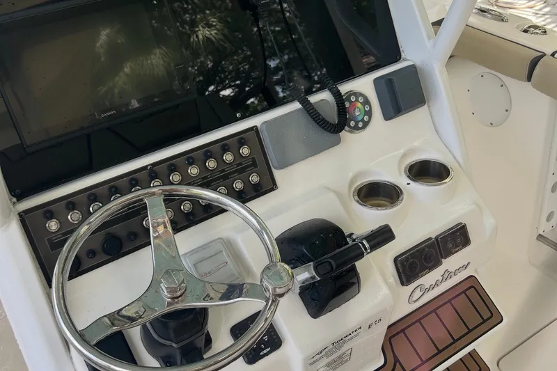 Slide: The Image of 2021 Tidewater 272 CC Adventure boat dashboard with steering wheel and controls. - 8