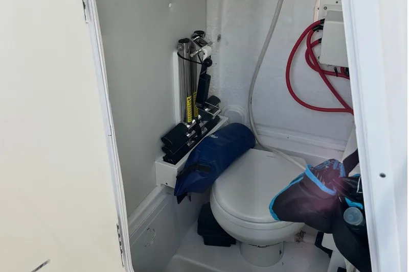 Slide: The Image of Interior of 2021 Tidewater 272 CC Adventure boat featuring compact marine toilet setup. - 16