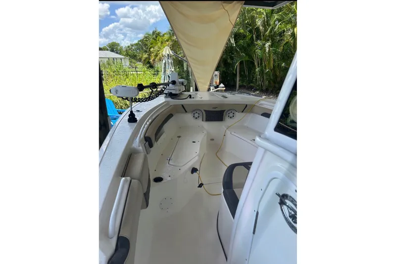Slide: The Image of 2021 Tidewater 272 CC Adventure boat interior with seating and steering, surrounded by lush greenery. - 5