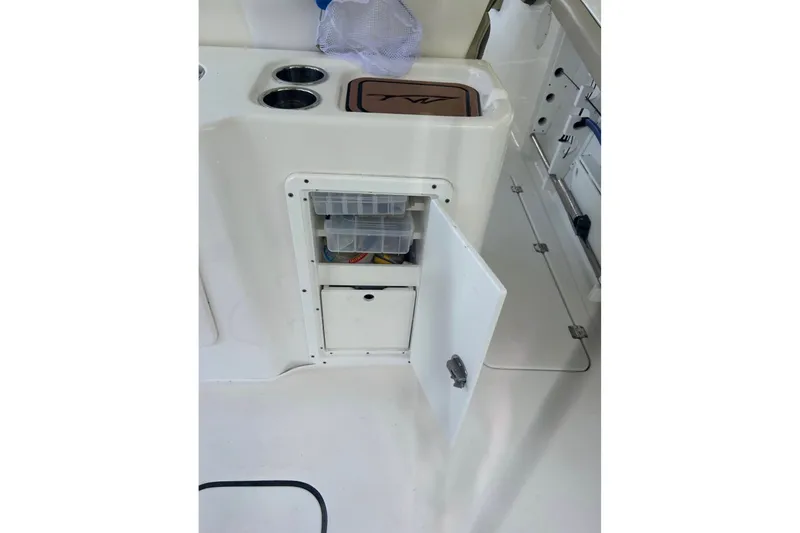 Slide: The Image of 2021 Tidewater 272 CC Adventure boat storage compartment with open door and organized containers. - 6