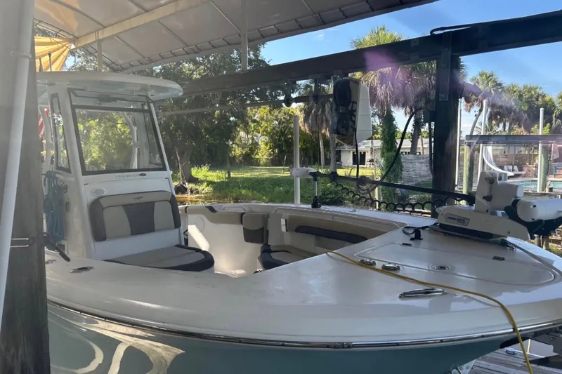 Slide: The Image of 2021 Tidewater 272 CC Adventure boat docked under a canopy with lush greenery. - 2