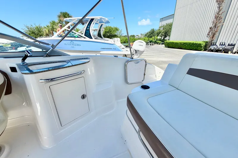 Slide: The Image of 2015 Chaparral 224 Sunesta boat interior with seating and storage, docked outdoors. - 10
