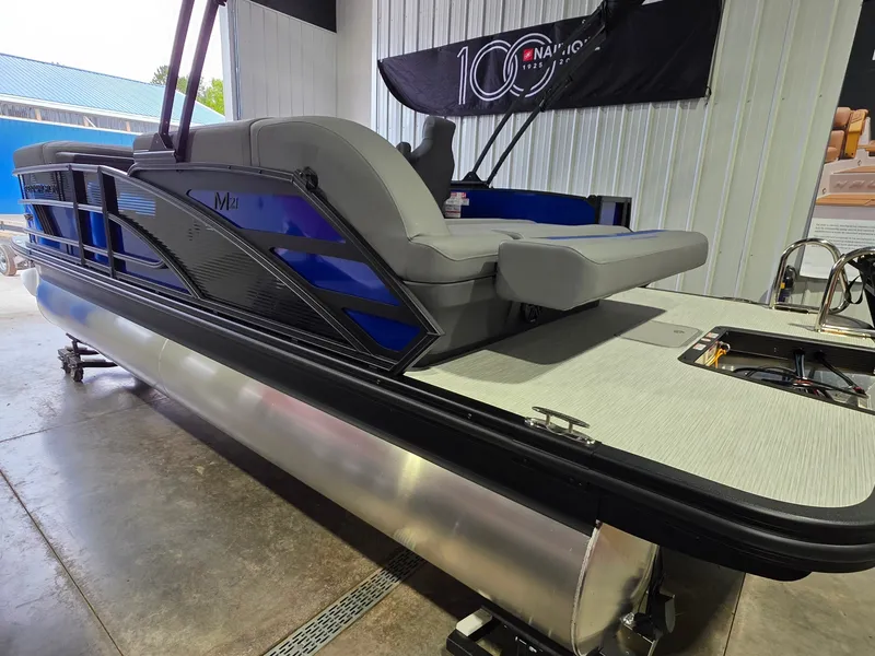 Slide: The Image of A 2027 Bennington 21ML SPS TRI pontoon boat in a showroom. It features gray upholstery and blue accents. - 4