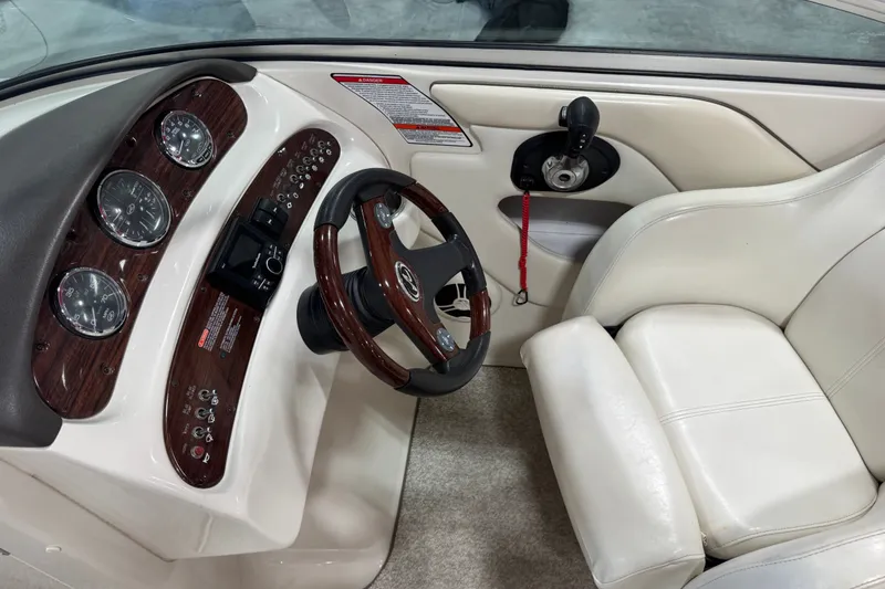 Slide: The Image of 2008 Sea Ray 240 Sundeck cockpit with wood-accented steering wheel and gauges. - 10