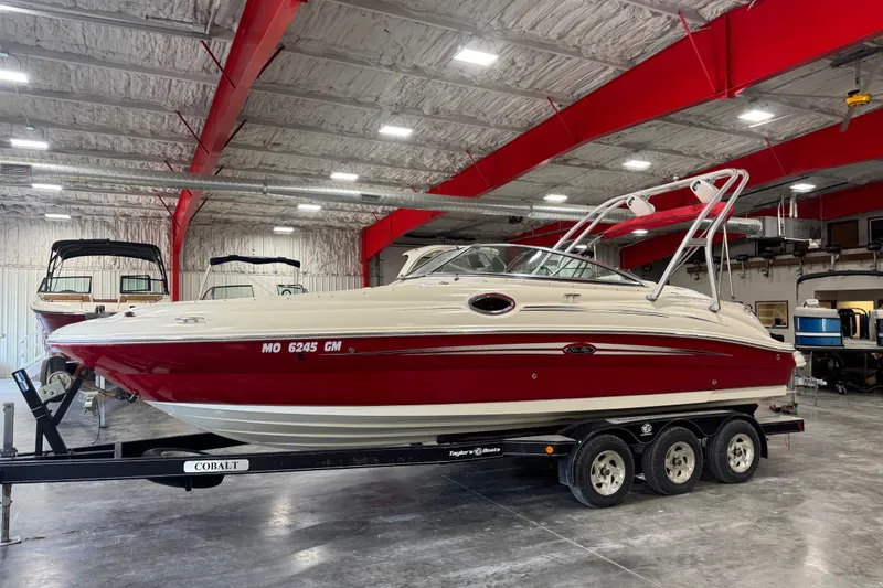 Slide: The Image of 2008 Sea Ray 240 Sundeck boat in a storage facility, red and white exterior. - 2