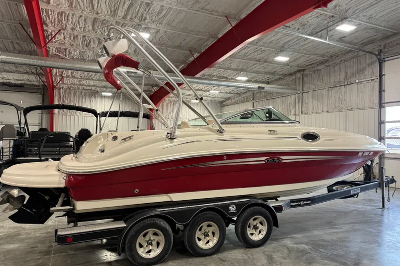Slide: The Image of 2008 Sea Ray 240 Sundeck boat in a garage, red and white exterior, on a trailer. - 4
