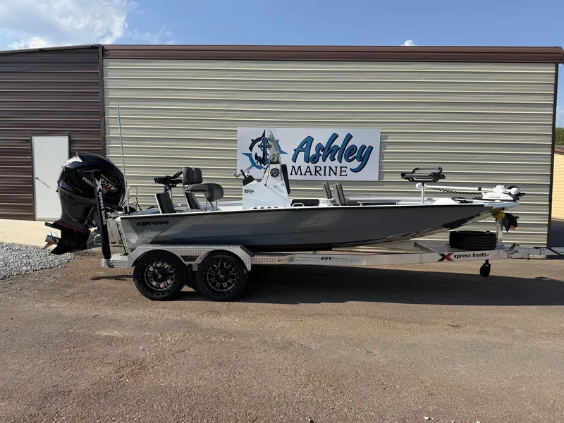 The Image of A gray Xpress Hyper-Lift Bay Series XR21 BAY boat on a trailer in front of a building. - 1