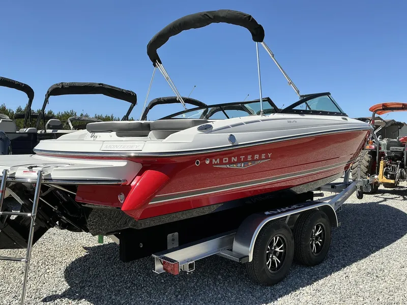 Slide: The Image of A red 2025 Monterey 224FS boat sits on a trailer in a gravel lot. - 2