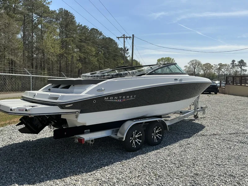 Slide: The Image of A 2025 Monterey M-22 boat on a trailer in a gravel lot. - 2