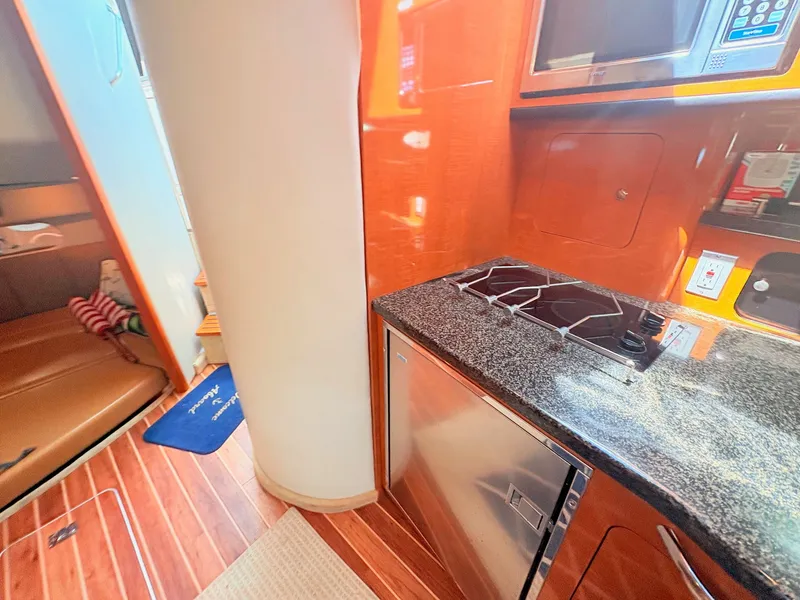 Slide: The Image of The interior of a 2007 Chaparral Signature 350 features a galley with a stove and refrigerator. - 17
