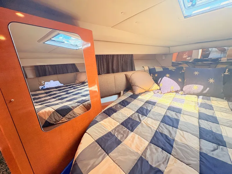 Slide: The Image of The 2007 Chaparral Signature 350 cabin features a cozy bed with checkered bedding. - 15