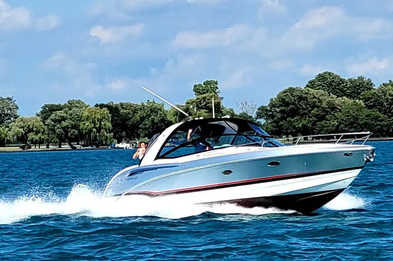 The Image of 2012 Formula 350 Sun Sport boat cruising on a sunny lake with lush green trees. - 0