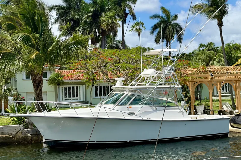 The Image of 2001 Henriques 35 Express boat docked near tropical waterfront home. - 1