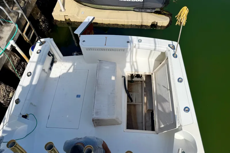 Slide: The Image of 2001 Henriques 35 Express boat deck with open storage compartment, docked by green water. - 22