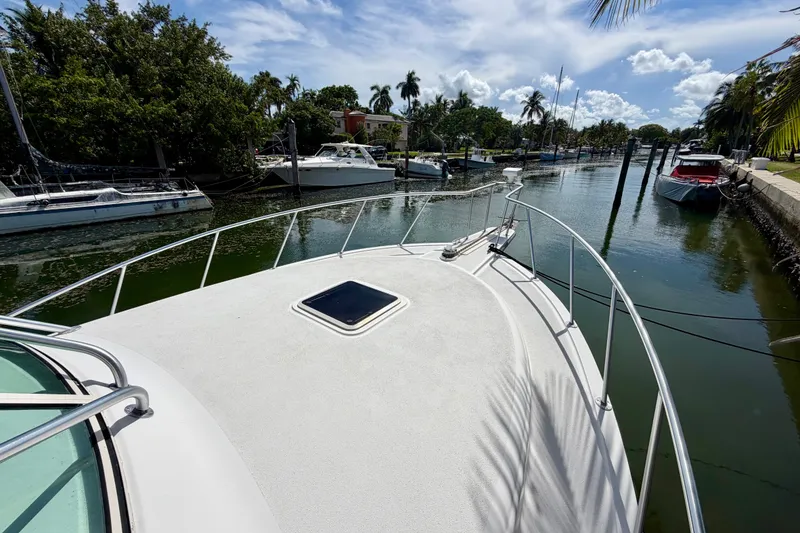 Slide: The Image of Bow view of a 2001 Henriques 35 Express yacht docked in a scenic canal. - 14