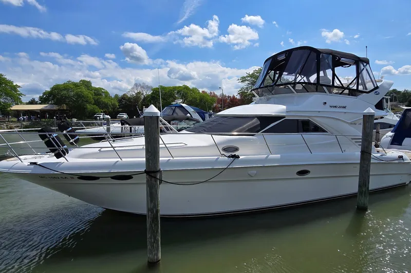 The Image of 2000 Sea Ray 400 Sedan Bridge yacht docked in a marina under a blue sky. - 1