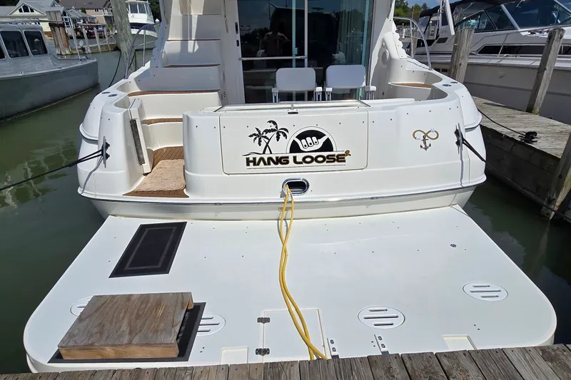 Slide: The Image of 2000 Sea Ray 400 Sedan Bridge docked, featuring "Hang Loose" logo on the stern. - 21