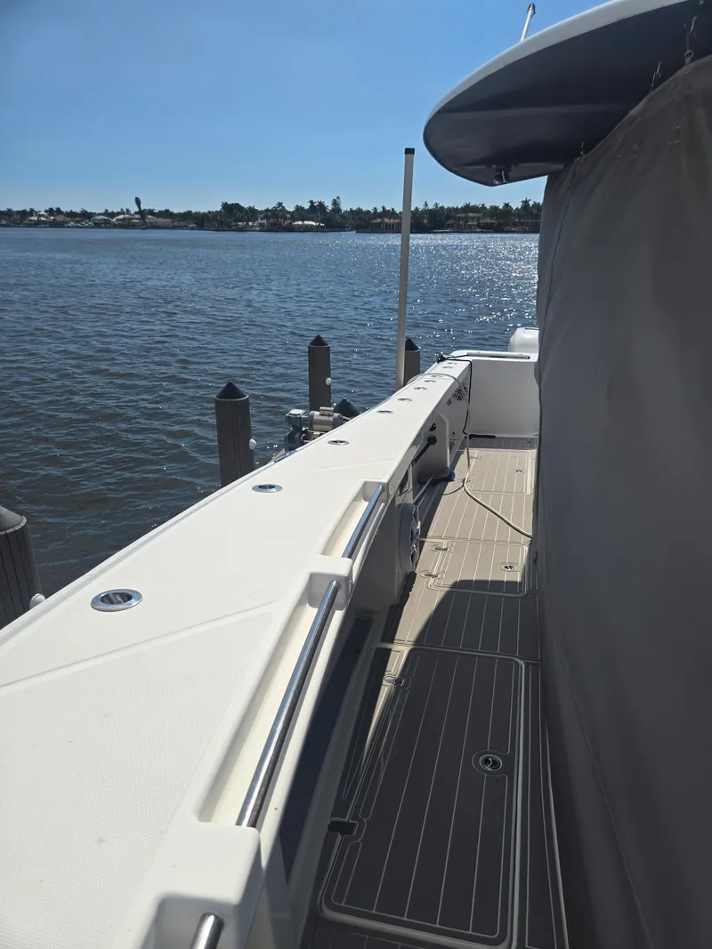 Slide: The Image of A modern boat with a white deck and gray flooring, docked by calm waters. - 12