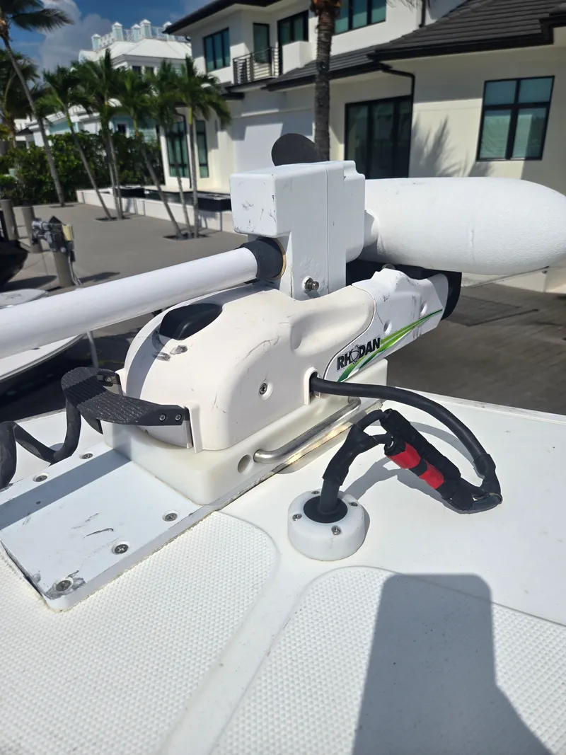 Slide: The Image of A modern boat with a white Riptide motor, building and palm trees in the background. - 11