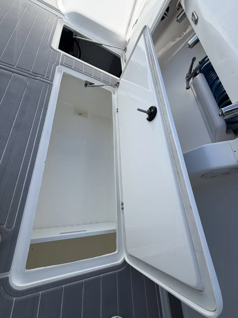 Slide: The Image of An open storage compartment on a boat with gray flooring and a white lid. - 24