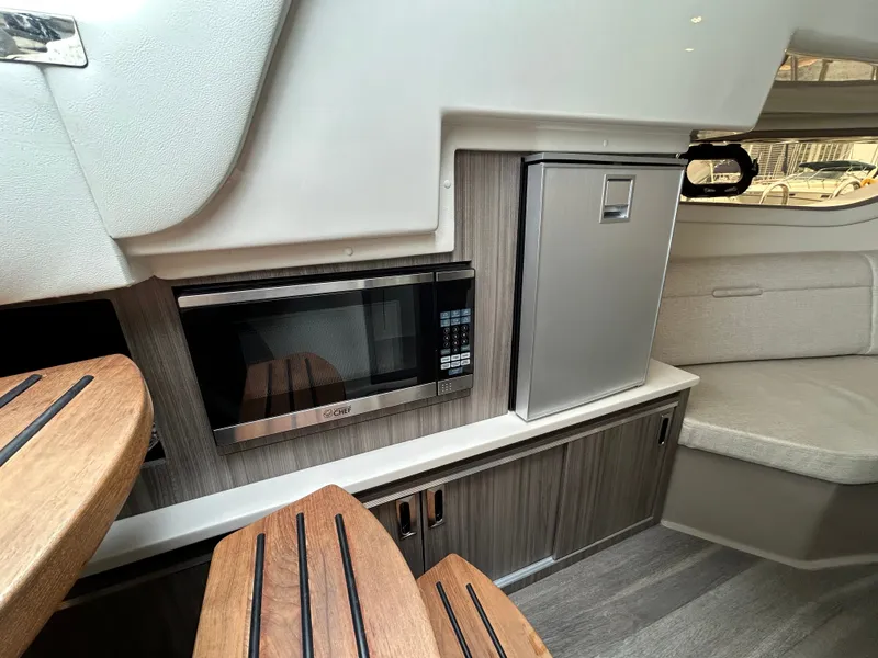 Slide: The Image of Interior of the Sea Ray Sundancer 320 with microwave and fridge, featuring modern wood paneling. - 19