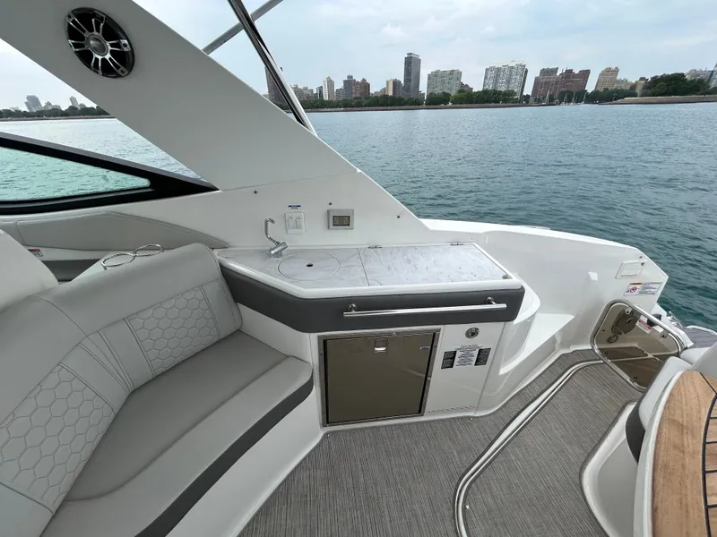 Slide: The Image of The image shows the cockpit of a 2023 Sea Ray Sundancer 320 with sleek seating and a small kitchenette. - 14