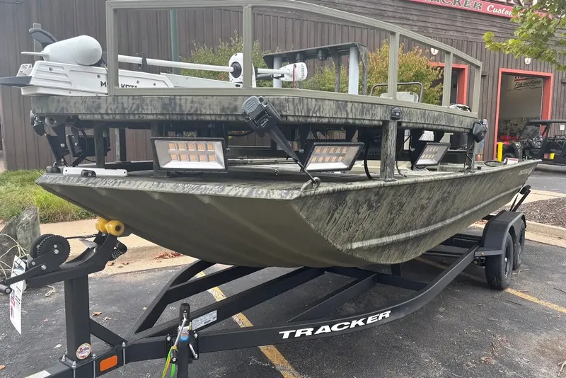 The Image of 2027 Tracker Grizzly 2072 CC Sportsman boat on trailer, parked outside a building. - 0