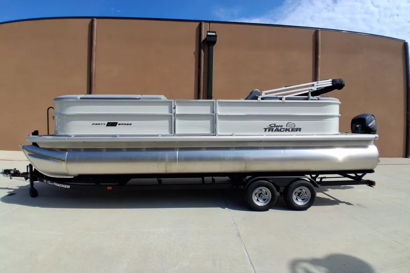 The Image of 2026 Sun Tracker Party Barge 24 XP3 pontoon boat on trailer, parked outdoors. - 0