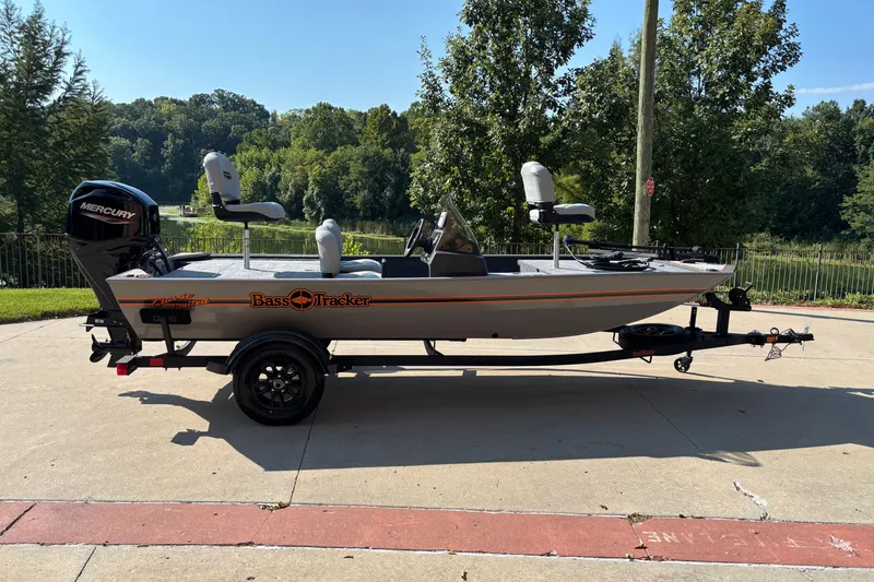 The Image of 2027 Tracker Bass Tracker Classic Limited boat on trailer, parked outdoors near trees. - 0