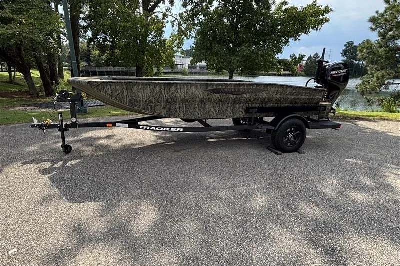 Slide: The Image of 2027 Tracker Grizzly 1650 T Prairie Wings Edition boat on trailer by a lake. - 17