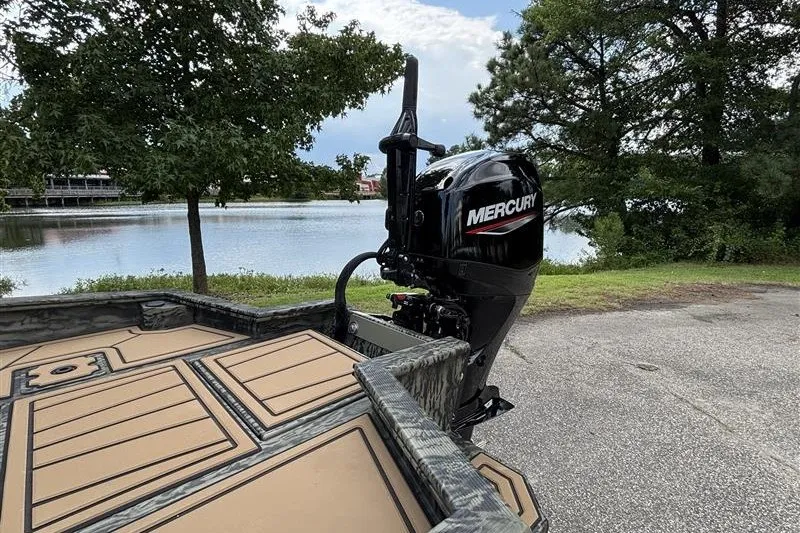 Slide: The Image of 2027 Tracker Grizzly 1650 T Prairie Wings Edition boat with Mercury outboard motor by a lake. - 14