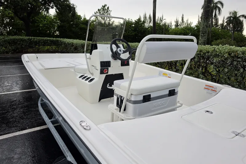 Slide: The Image of 2027 Mako Pro Skiff 17 CC boat with center console and seating in a parking lot. - 6