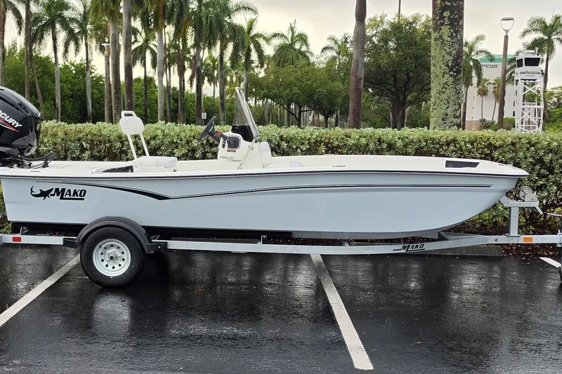 Slide: The Image of 2027 Mako Pro Skiff 17 CC boat on trailer, parked outdoors with palm trees. - 1