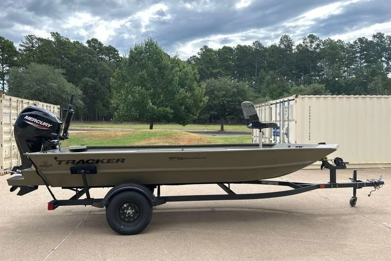 Slide: The Image of 2027 Tracker Grizzly 1654 T Sportsman boat on trailer, outdoors with trees in background. - 13