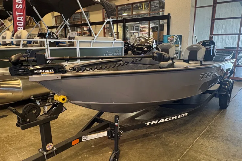 The Image of 2027 Tracker Super Guide V-16 SC fishing boat displayed in showroom with Minn Kota trolling motor. - 0