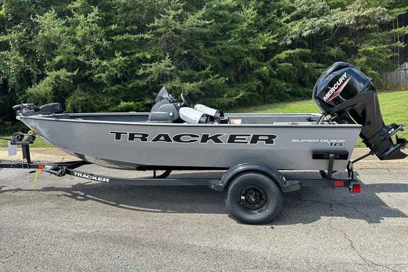The Image of 2027 Tracker Super Guide V-16 SC boat on trailer, parked outdoors. - 0