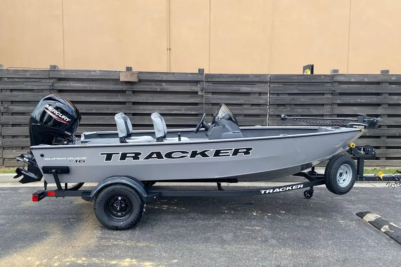 The Image of 2027 Tracker Super Guide V-16 SC fishing boat on trailer, parked outdoors. - 0