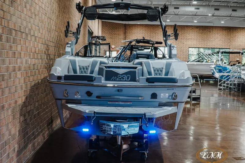 Slide: The Image of 2027 Malibu M230 boat in showroom, featuring sleek design and advanced wakeboarding equipment. - 10