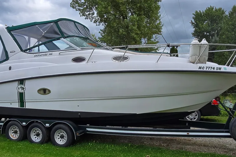 The Image of 1998 Chaparral Signature 300 boat on trailer, parked outdoors with trees in background. - 1