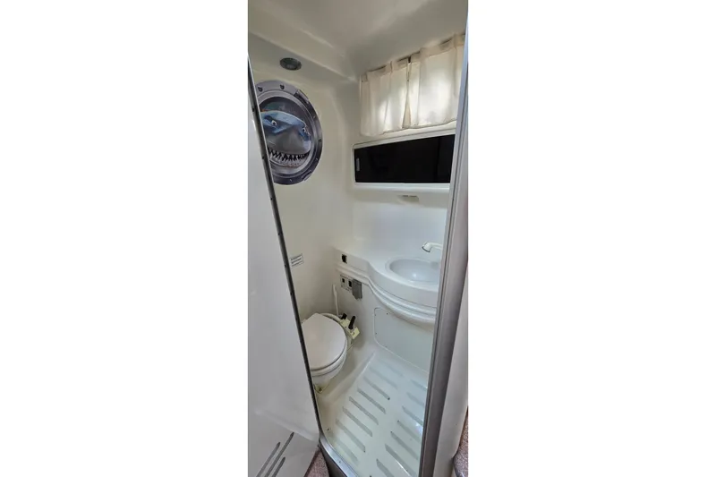 Slide: The Image of 1998 Chaparral Signature 300 boat bathroom with toilet, sink, and porthole window. - 27