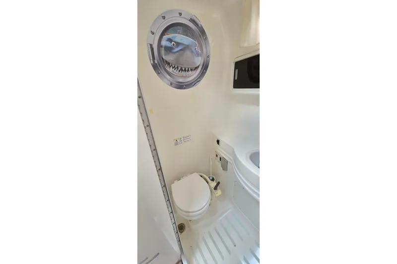 Slide: The Image of 1998 Chaparral Signature 300 boat bathroom with porthole and toilet. - 29