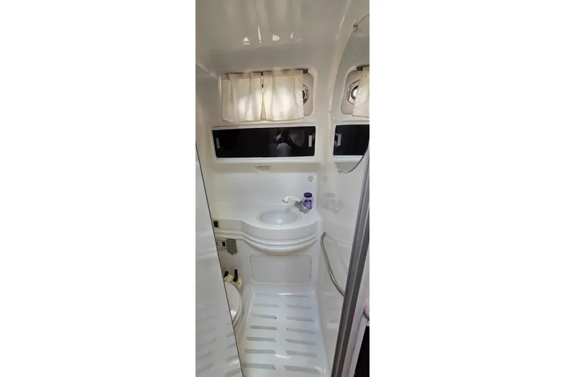 Slide: The Image of 1998 Chaparral Signature 300 boat bathroom with sink, mirror, and porthole windows. - 28